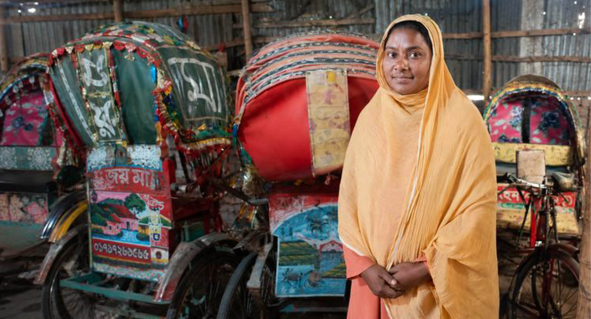 Shahana Akter Khushi standing in front of her rickshaws